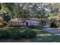 Charming ranch-style home with manicured landscaping and an attached garage nestled among mature trees at 4042 Shady Nw Cir, Lilburn, GA 30047