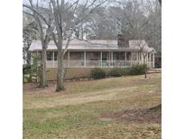 Charming ranch-style home featuring a long porch, metal roof, and a stone chimney at 582 S Cherokee Rd, Social Circle, GA 30025