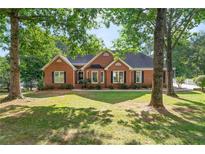 Charming brick home with black shutters, a manicured lawn, and mature trees in a peaceful setting at 587 Morgan Ct, Hampton, GA 30228