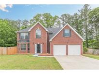Charming two-story brick home featuring a two-car garage, manicured lawn, and a classic, welcoming facade at 105 Kentwood Springs Dr, Hampton, GA 30228