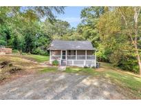 Charming cottage-style home featuring a screened front porch and a lush, wooded lot at 4481 Mclain Cir, Acworth, GA 30101