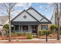 Charming home with a stone and gray facade, complemented by a welcoming front porch and well-maintained landscaping at 830 Village Manor Pl, Suwanee, GA 30024