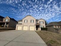 Traditional two-story brick home with a three car garage and a concrete driveway at 7686 Brazos Trl, Fairburn, GA 30213