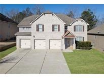 Charming two-story brick home featuring a three-car garage and well-manicured lawn at 7686 Brazos Trl, Fairburn, GA 30213