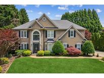 Charming two-story home featuring manicured landscaping, lush lawn, and mature trees at 2115 Brook Pond Ct, Alpharetta, GA 30005