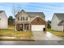 Two-story home with brick and tan siding, a two-car garage, and a well-maintained lawn at 2376 Allman Dr, Jonesboro, GA 30236