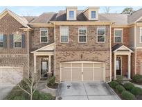 Exterior of a brick townhome featuring a two-car garage, covered entrance, and well-maintained landscaping at 2286 Emerald Sky Dr, Smyrna, GA 30080
