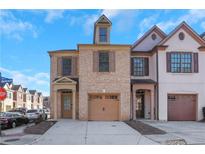 Charming brick townhome with a two-car garage, neutral trim, and a well-maintained facade at 300 Knelston Oak Dr, Suwanee, GA 30024