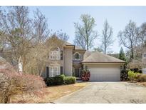 Charming two-story home with a well-manicured lawn, blooming bushes, and a two-car garage at 135 Belmont Trce, Atlanta, GA 30328