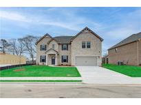 Charming two-story brick home featuring a manicured lawn and a two-car garage at 200 Haverling Pass, Hampton, GA 30228