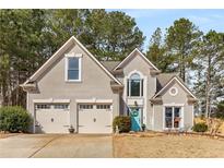 Charming two-story home featuring a well-manicured lawn, an attached garage, and a welcoming, bright blue front door at 1027 Deer Hollow Dr, Woodstock, GA 30189