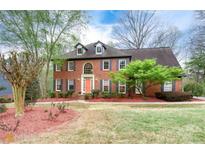 Charming two-story brick home with a manicured lawn and a bright orange front door at 2881 Riverfront Dr, Snellville, GA 30039