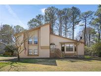 Two-story tan home with gable roof, brick facade, front porch, and manicured lawn at 425 Ridgemont Dr, Lawrenceville, GA 30046