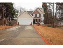 Inviting two-story home features a brick and vinyl exterior, two-car garage, and a well-manicured front lawn at 402 Rising Cir, Woodstock, GA 30189