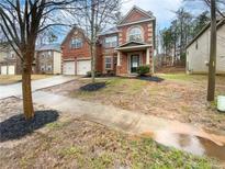 Charming two-story brick home featuring a two-car garage, front porch, and landscaped yard at 6503 Foggy Oak Dr, Fairburn, GA 30213
