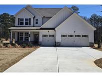 Charming two-story home featuring a two-car garage, inviting front porch, and crisp white siding at 14 Ramble Way, Sharpsburg, GA 30277