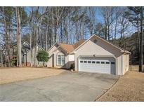 Charming single-story home with attached two-car garage and well-maintained lawn surrounded by mature trees at 606 Wedgewood Dr, Woodstock, GA 30189