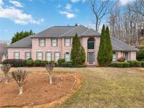 Elegant brick home featuring a well-manicured lawn, mature trees, and a symmetrical facade at 3605 Summit Gate Dr, Suwanee, GA 30024