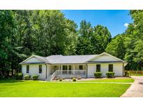 Charming white ranch home with a covered porch and lush green lawn, surrounded by mature trees at 140 Pine Glade Trce, Roswell, GA 30075