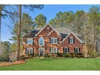 Charming two-story brick home with a well-manicured lawn and mature trees at 7115 Doncaster Ct, Cumming, GA 30040