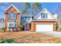 Charming two-story home boasts a brick and white facade, attached two-car garage and well-manicured front yard at 5055 Hampton Bluff Ct, Roswell, GA 30075