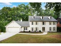 Charming two-story home with a manicured lawn, dormer windows, attached garage, and mature trees at 2958 Cravey Ne Dr, Atlanta, GA 30345