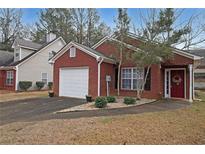 Charming red brick home featuring an attached garage, landscaped front yard and a welcoming red front door at 5989 Zane Ct, Douglasville, GA 30135