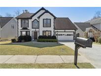 Charming two-story home featuring black and white trim, a well-manicured lawn, and an attached two-car garage at 2882 Manor Glen Ln, Suwanee, GA 30024