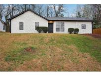 Charming single-story home with a stone facade, a black front door, and fresh landscaping at 5151 Martins Crossing Rd, Stone Mountain, GA 30088