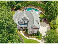 Stunning aerial view of a brick home with a pool, hot tub, and lush landscaping at 10275 Worthington Mnr, Suwanee, GA 30024