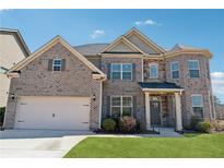 Beautiful brick two-story home with attached two-car garage and manicured lawn on a sunny day at 590 Palm Springs Cir, Fairburn, GA 30213