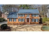 Traditional red brick home with a blue roof, green shutters and manicured landscaping at 4335 Halifax Ne Ter, Roswell, GA 30075