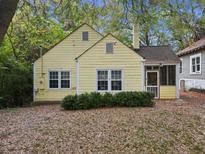 Charming yellow cottage-style home featuring double-pane windows, mature trees, and a cozy front porch at 909 Morris Nw St, Atlanta, GA 30318