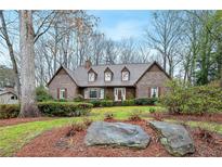 Charming brick home featuring a manicured front yard with mature trees and lush landscaping at 50 Stonington Pl, Marietta, GA 30068