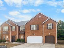 Charming two-story brick home with a well-manicured lawn and an attached two-car garage at 5589 Dendy Trace, Fairburn, GA 30213