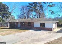 Traditional brick home with a concrete driveway and mature trees against a clear blue sky at 6258 Mount Zion Blvd, Morrow, GA 30260