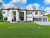 Stunning modern home featuring a crisp white facade, expansive windows, and a meticulously manicured lawn at 2940 Old Peachtree Rd, Dacula, GA 30019