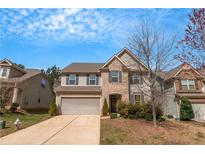 Charming two-story home with a manicured lawn, attached garage, and a combination of stone and siding at 1077 Roanoke Ave, Mcdonough, GA 30253