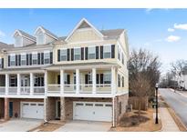 Charming yellow townhome featuring black shutters, a covered porch, and a private garage at 403 Inglenook Walk, Marietta, GA 30060