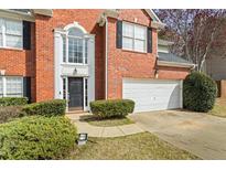 Close up of the front of a brick home with a black door and a two-car garage at 1390 Bridle Path Dr, Lawrenceville, GA 30045