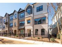Attractive townhome exterior featuring brick and siding, a black metal fence, and manicured landscaping at 710 Hudson Way, Roswell, GA 30076