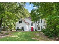 Charming two-story home with a manicured lawn, mature trees, and a vibrant red front door at 76 Barrington Farms Pkwy, Sharpsburg, GA 30277