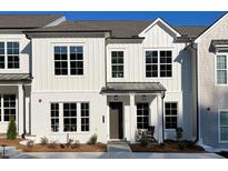 Charming two-story townhouse with white brick, board and batten, black trim, and a cozy front porch at 312 Thistle Ct, Woodstock, GA 30189