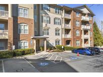 Apartment building exterior view showing accessible parking spaces, landscaped bushes, and column-supported entryway at 4805 W Village Se Way # 2108, Smyrna, GA 30080