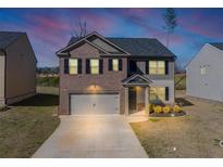 Two-story home features a two car garage, brick and siding exterior, and professionally landscaped front yard at 1540 Denver Way, Locust Grove, GA 30248