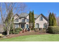 Charming brick home featuring manicured lawn, mature trees, and a traditional architectural design at 11020 Bradford Ln, Suwanee, GA 30024