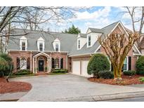 Beautiful brick home featuring dormer windows, a two-car garage, and mature landscaping at 1207 Woodlawn Ne Dr, Marietta, GA 30068