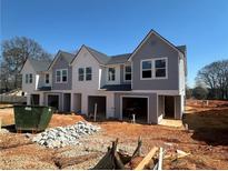 New construction townhomes featuring a two-tone exterior with private garage spaces and unfinished front yards at 11602 E Lovejoy Rd, Hampton, GA 30228