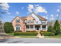 Beautiful brick home with covered front porch and manicured landscaping under a partly cloudy blue sky at 4865 Meadow Park Ln, Suwanee, GA 30024