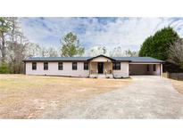 Charming renovated ranch-style home with a painted brick exterior and covered carport on a sunny day at 2177 American Legion Rd, Dacula, GA 30019